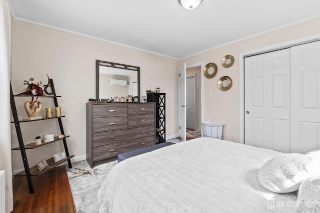 bedroom featuring crown molding, wood finished floors, baseboards, a closet, and an AC wall unit