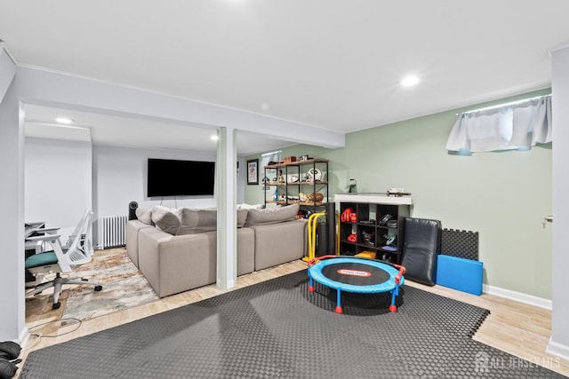 recreation room with recessed lighting, baseboards, radiator, and wood finished floors