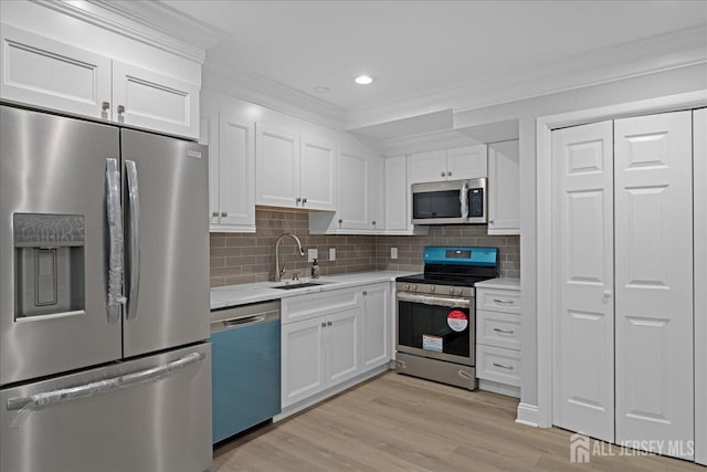 kitchen with ornamental molding, sink, stainless steel appliances, and white cabinetry