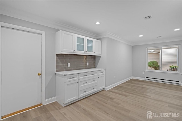 kitchen featuring baseboard heating, ornamental molding, light wood-type flooring, and white cabinets