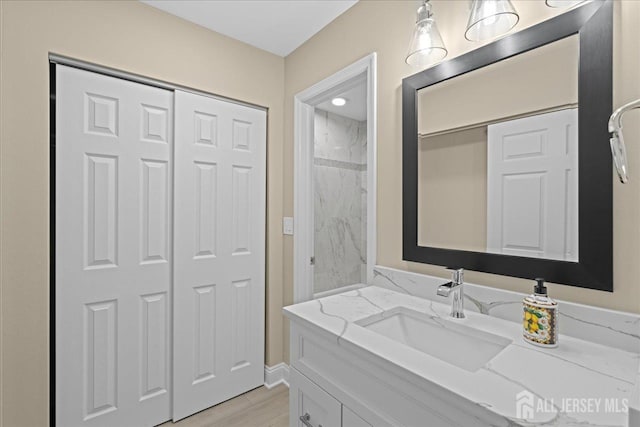 bathroom featuring hardwood / wood-style flooring, vanity, and a shower