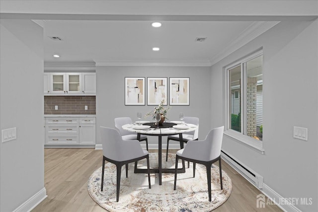 dining room with light wood-type flooring, baseboard heating, and ornamental molding