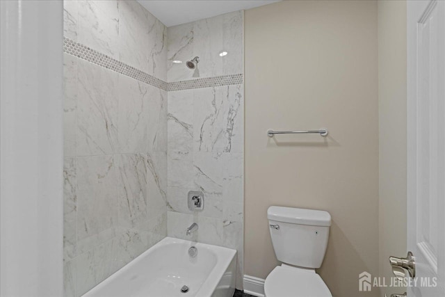 bathroom featuring toilet and tiled shower / bath