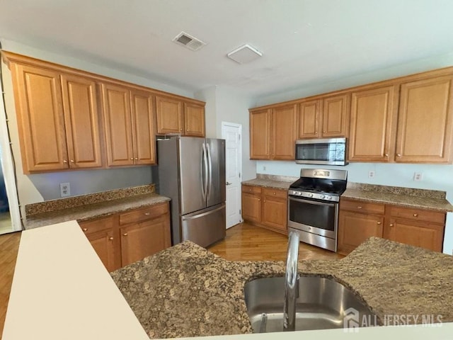 51 S Shore Dr, South Amboy, NJ 08879 - kitchen with appliances with stainless steel finishes, a sink, wood finished floors, dark stone counters, and brown cabinets