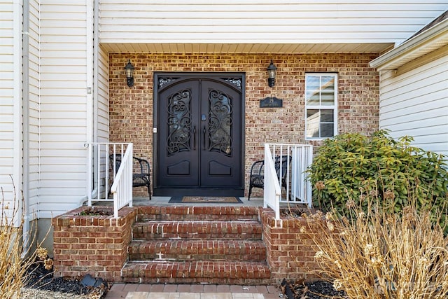 view of exterior entry with covered porch and brick siding