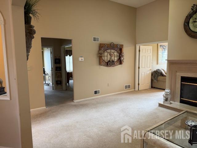 102 Leeds Ln, Monroe, NJ 08831 - unfurnished living room with carpet flooring, a glass covered fireplace, high vaulted ceiling, and arched walkways