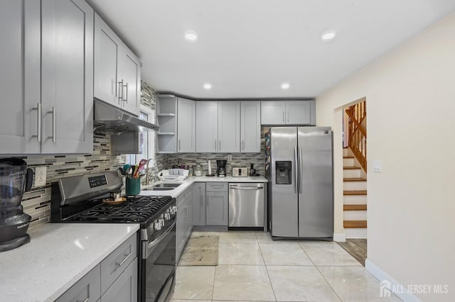 kitchen featuring gray cabinets, sink, stainless steel appliances, and tasteful backsplash