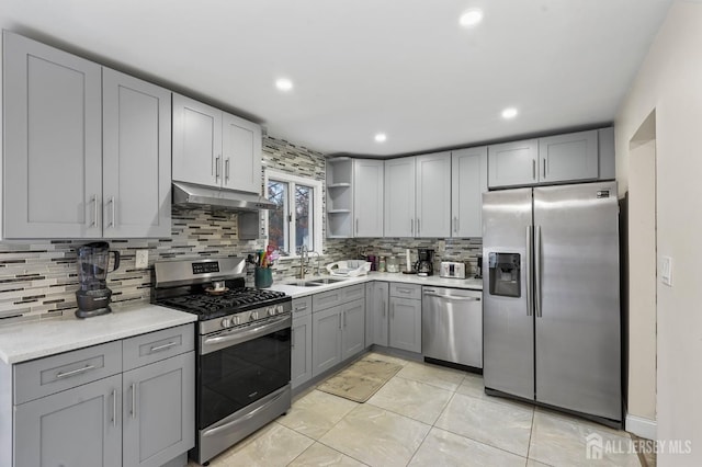 kitchen featuring decorative backsplash, stainless steel appliances, gray cabinetry, and sink