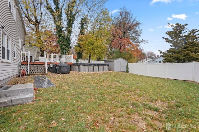 view of yard featuring a wooden deck and a storage unit