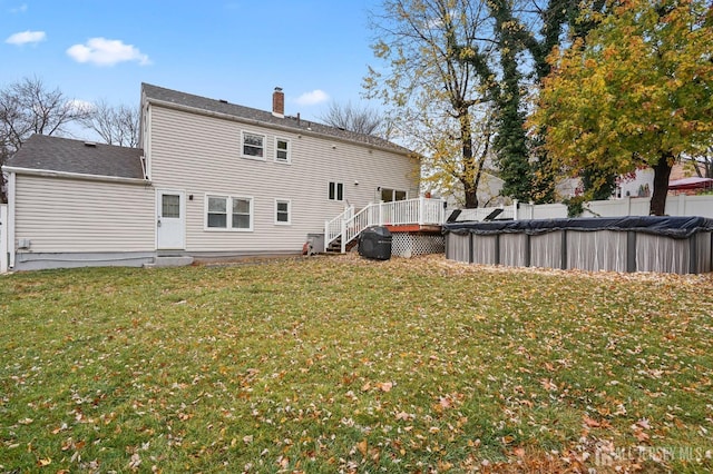 rear view of property with a swimming pool side deck and a lawn