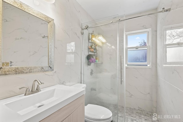 bathroom with vanity, a shower with shower door, tile walls, and toilet