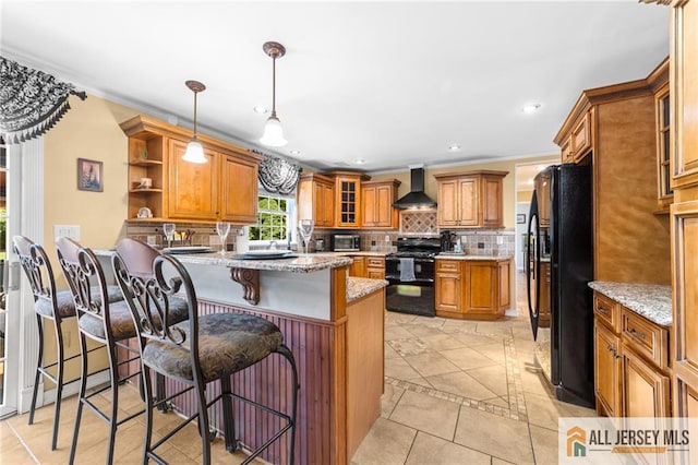 21 Tanglewood Pl, Monroe, NJ 08831 - kitchen featuring black appliances, wall chimney range hood, brown cabinetry, a peninsula, and tasteful backsplash
