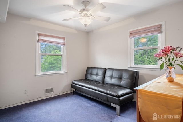 living area featuring a ceiling fan, visible vents, and carpet floors