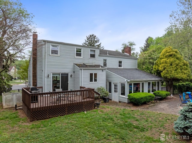 rear view of property with a chimney, a wooden deck, and a patio