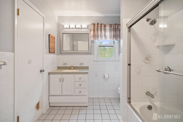 full bath featuring tile walls, tile patterned flooring, toilet, vanity, and enclosed tub / shower combo