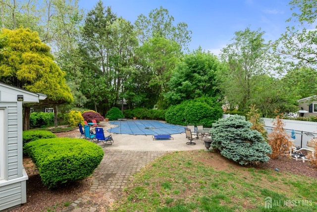 view of pool featuring a patio area, fence, and view of wooded area