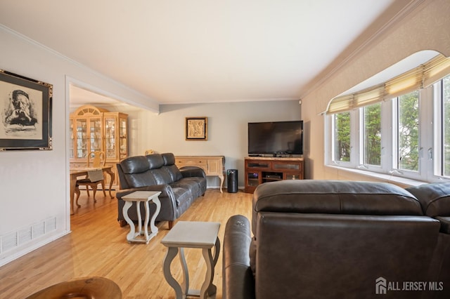 living room with ornamental molding, visible vents, and light wood-style floors
