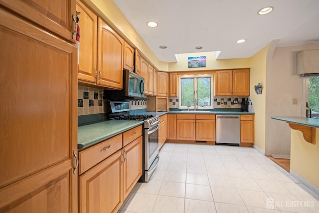 kitchen featuring appliances with stainless steel finishes, a sink, tasteful backsplash, recessed lighting, and light tile patterned floors