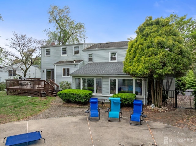 back of house featuring a deck, a patio, fence, and a shingled roof