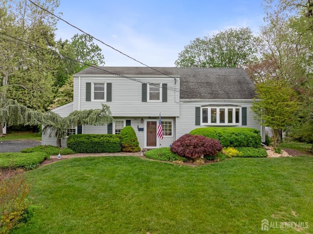 split level home with a front yard and roof with shingles