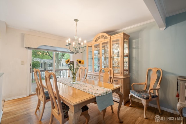 dining area featuring crown molding, light wood-style flooring, a notable chandelier, and baseboards