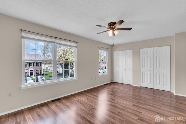 19 Albury Way N, Brunswick, NJ 08902 - unfurnished bedroom featuring multiple closets, wood finished floors, a textured ceiling, baseboards, and ceiling fan