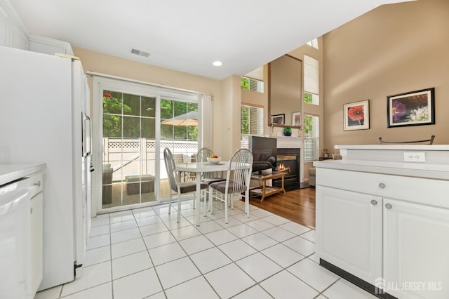 44 Windsong Cir E, Brunswick, NJ 08816 - kitchen with white appliances, white cabinetry, light countertops, a glass covered fireplace, and light tile patterned flooring
