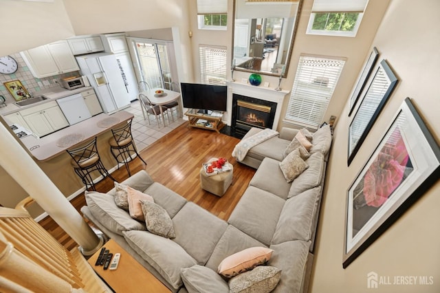 44 Windsong Cir E, Brunswick, NJ 08816 - living area featuring a towering ceiling, plenty of natural light, a fireplace, and light wood finished floors