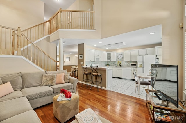 44 Windsong Cir E, Brunswick, NJ 08816 - living room with light wood-style flooring, a towering ceiling, decorative columns, stairway, and recessed lighting