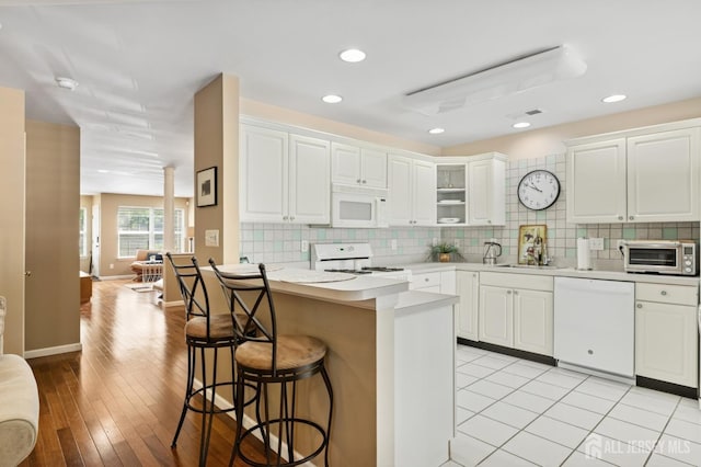 44 Windsong Cir E, Brunswick, NJ 08816 - kitchen featuring white appliances, a breakfast bar area, light countertops, backsplash, and white cabinetry
