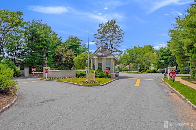 47 Park Gate Dr, Edison, NJ 08820 - view of asphalt road with traffic signs, a gated entry, curbs, and a speed bump