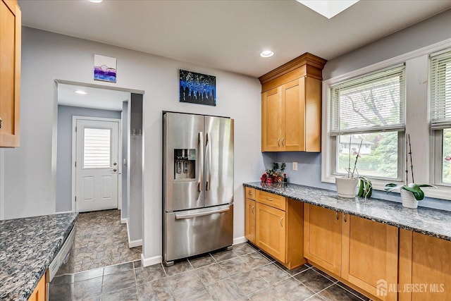 kitchen with appliances with stainless steel finishes, dark stone counters, recessed lighting, baseboards, and brown cabinetry