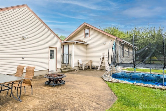 back of house with a trampoline, an outdoor fire pit, a patio area, and entry steps