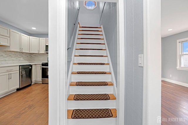 stairs with baseboards, wood finished floors, and recessed lighting