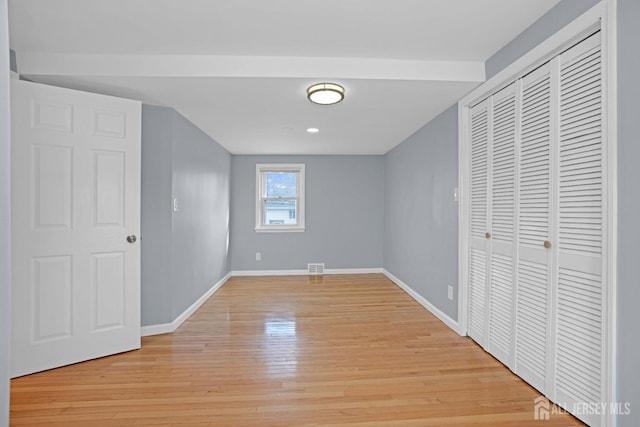 unfurnished bedroom with a closet, light wood-type flooring, visible vents, and baseboards