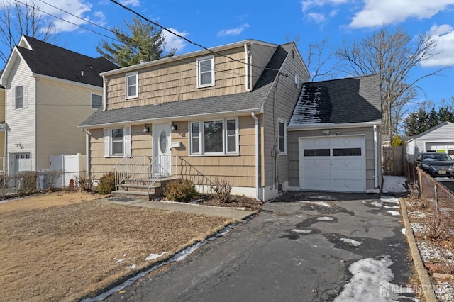 view of front of home featuring a garage, driveway, fence, and roof with shingles