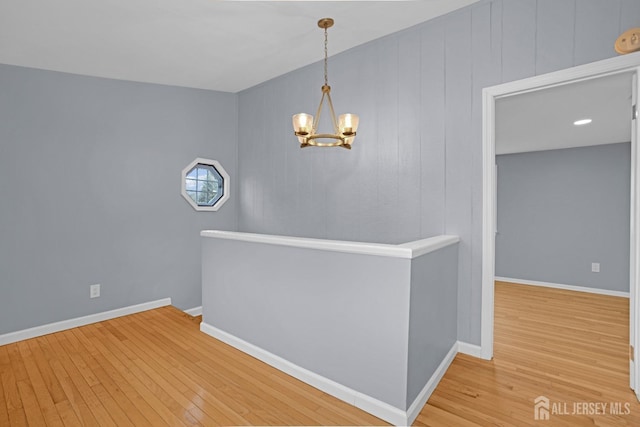 interior space featuring baseboards, wood-type flooring, an upstairs landing, and an inviting chandelier