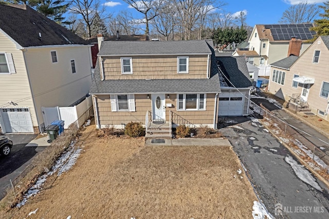 view of front facade featuring an attached garage, a shingled roof, fence, driveway, and a residential view