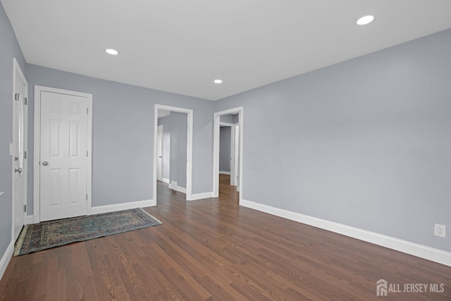 spare room with recessed lighting, dark wood-style flooring, and baseboards