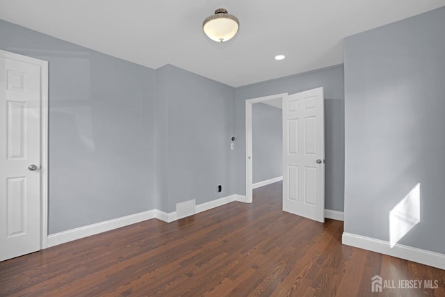 spare room featuring wood finished floors, visible vents, and baseboards