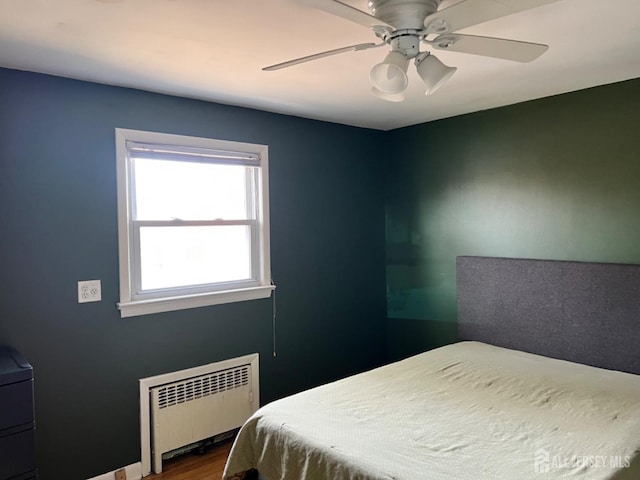 bedroom with radiator, hardwood / wood-style floors, and ceiling fan