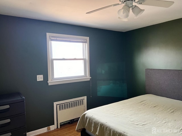 bedroom with wood-type flooring, radiator heating unit, and ceiling fan