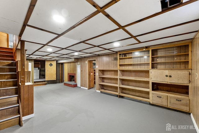 finished basement with washer / dryer, a brick fireplace, wooden walls, and stairs