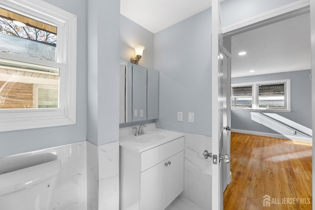 half bath featuring toilet, wood finished floors, and vanity