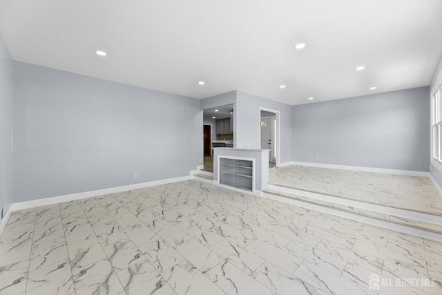 unfurnished living room featuring recessed lighting, marble finish floor, and baseboards