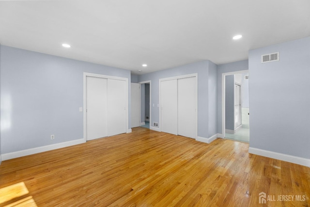 interior space with recessed lighting, visible vents, baseboards, light wood finished floors, and two closets