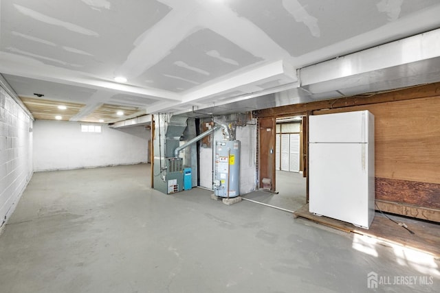 basement with heating unit, gas water heater, and freestanding refrigerator