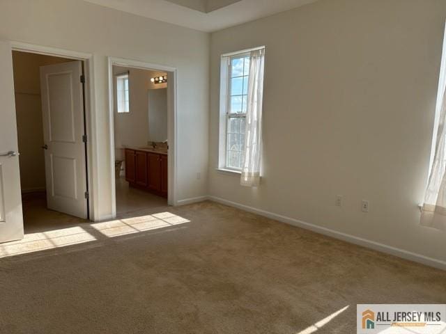 unfurnished bedroom with baseboards, multiple windows, and carpet