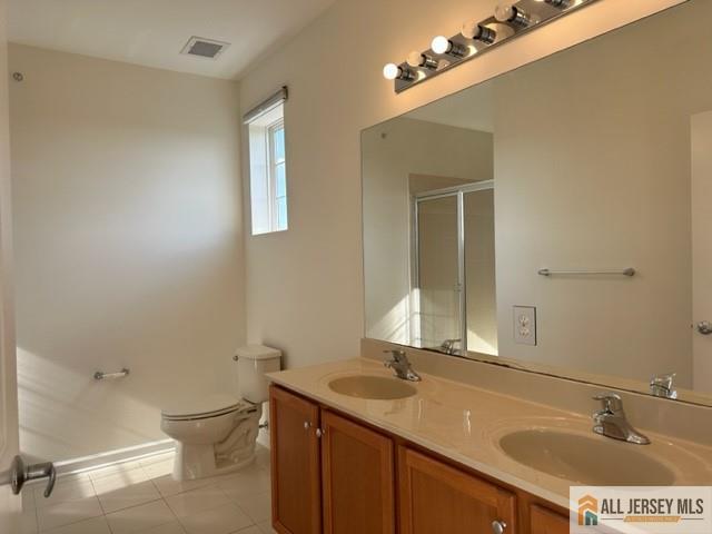 bathroom featuring tile patterned floors, walk in shower, vanity, and toilet