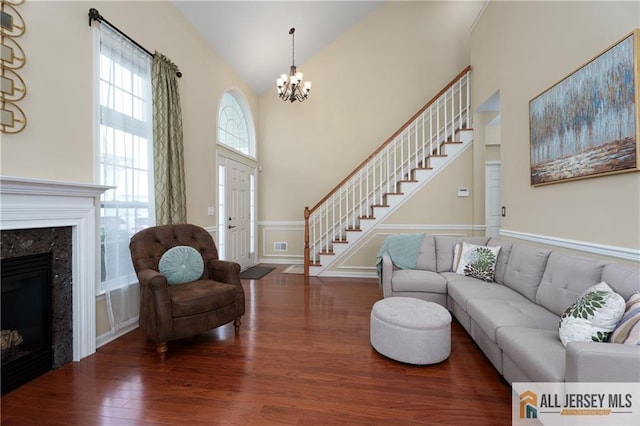 704 Schindler Dr, South Brunswick, NJ 08852 - living room featuring stairway, wood finished floors, a chandelier, a premium fireplace, and high vaulted ceiling